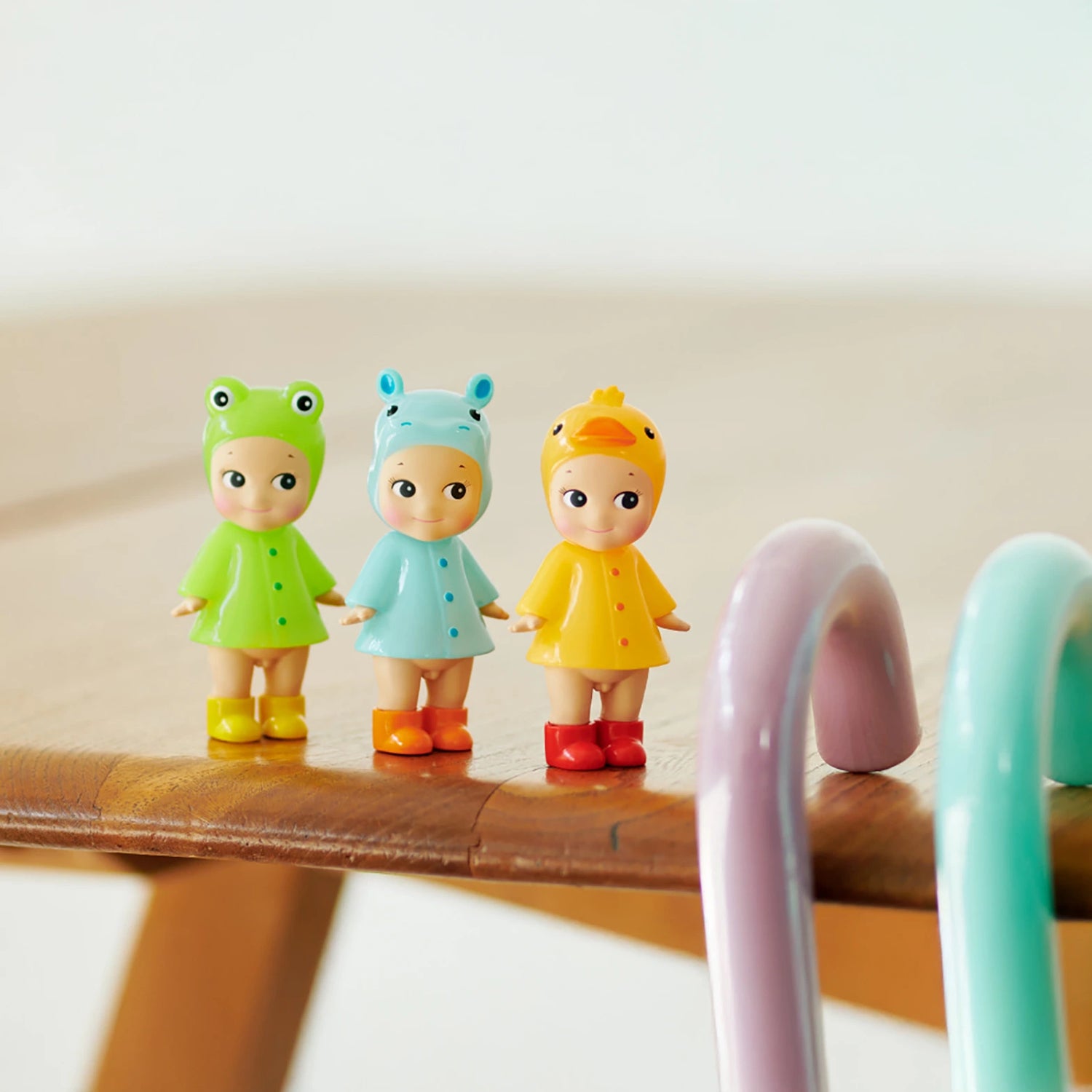 Three limited edition Sonny Angel Rainy Day Blind Box dolls by Sonny Angel, each in unique animal-themed costumes, are displayed side by side on a wooden surface near pastel curved props—perfect for Blind Box fans and collectors.