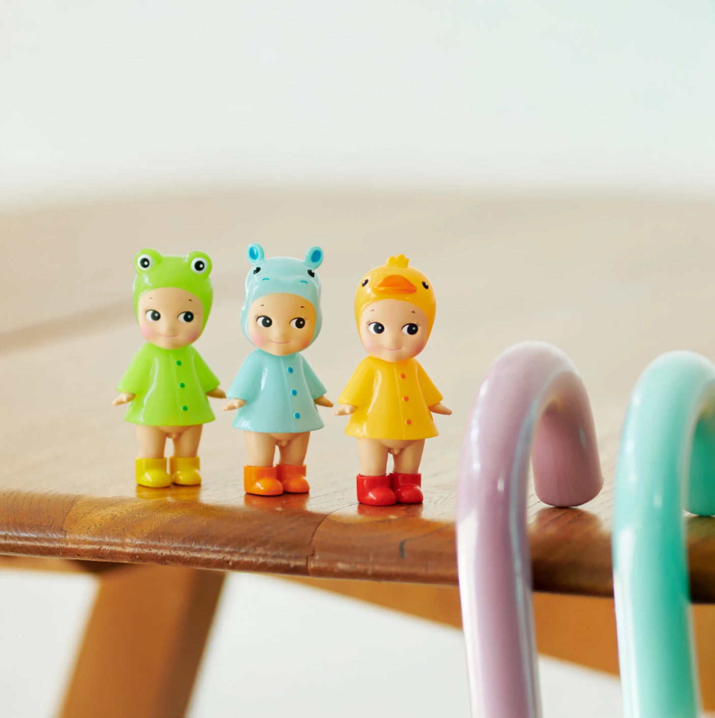 Three limited edition Sonny Angel Rainy Day Blind Box dolls by Sonny Angel, each in unique animal-themed costumes, are displayed side by side on a wooden surface near pastel curved props—perfect for Blind Box fans and collectors.