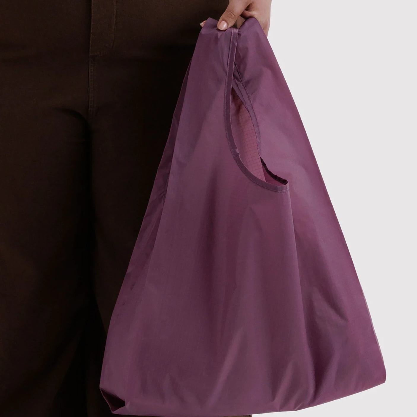 Baggu Standard reusable bag in wild plum, held open with side pocket and short handles