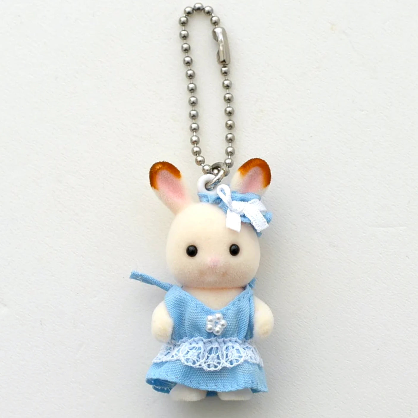 White plush baby rabbit keychain with blue dress, bow, and silver bead ball chain