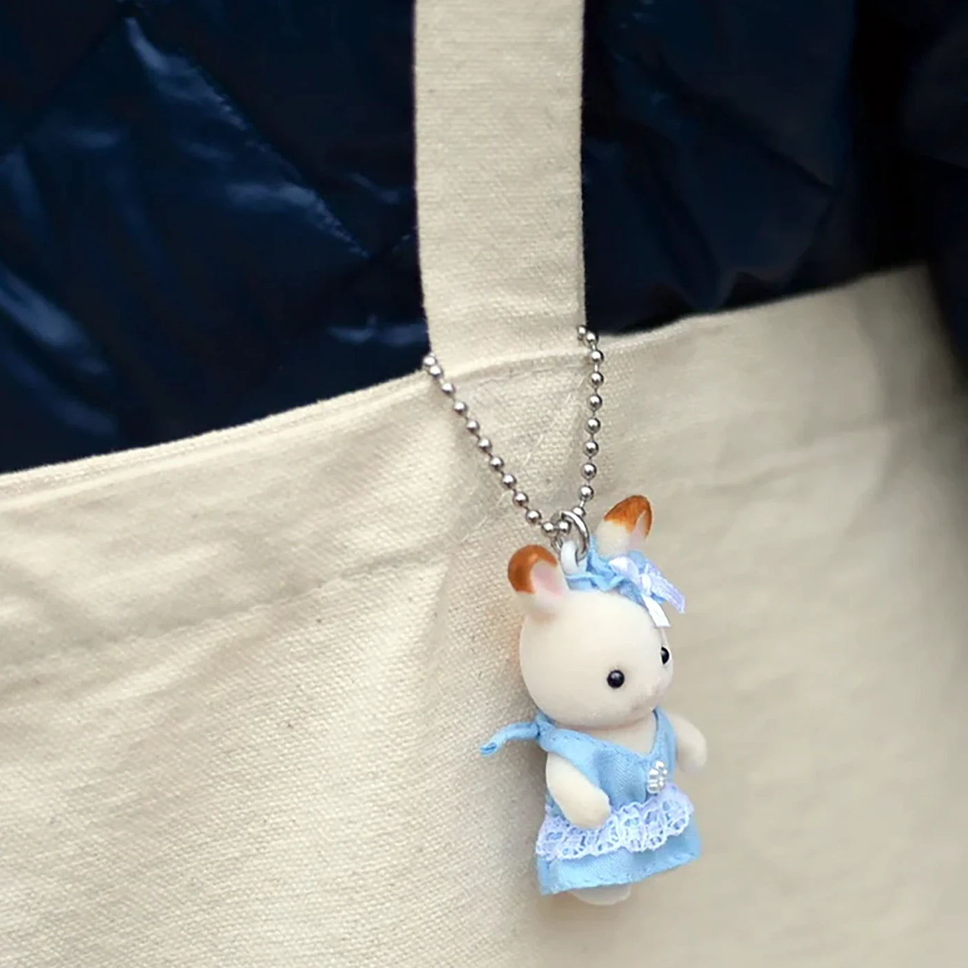 Plush baby rabbit keychain charm in blue dress hanging on silver ball chain