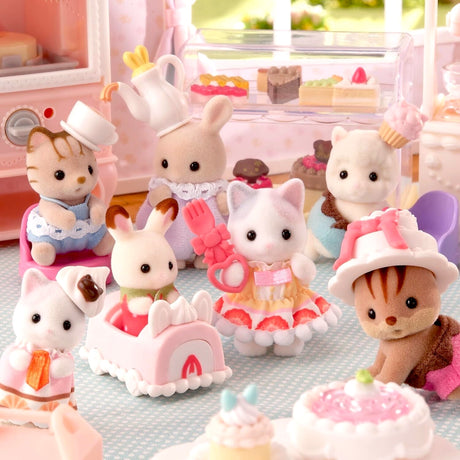 A group of small, plush animal figures in a detailed, toy bakery setting with cakes and pastries.