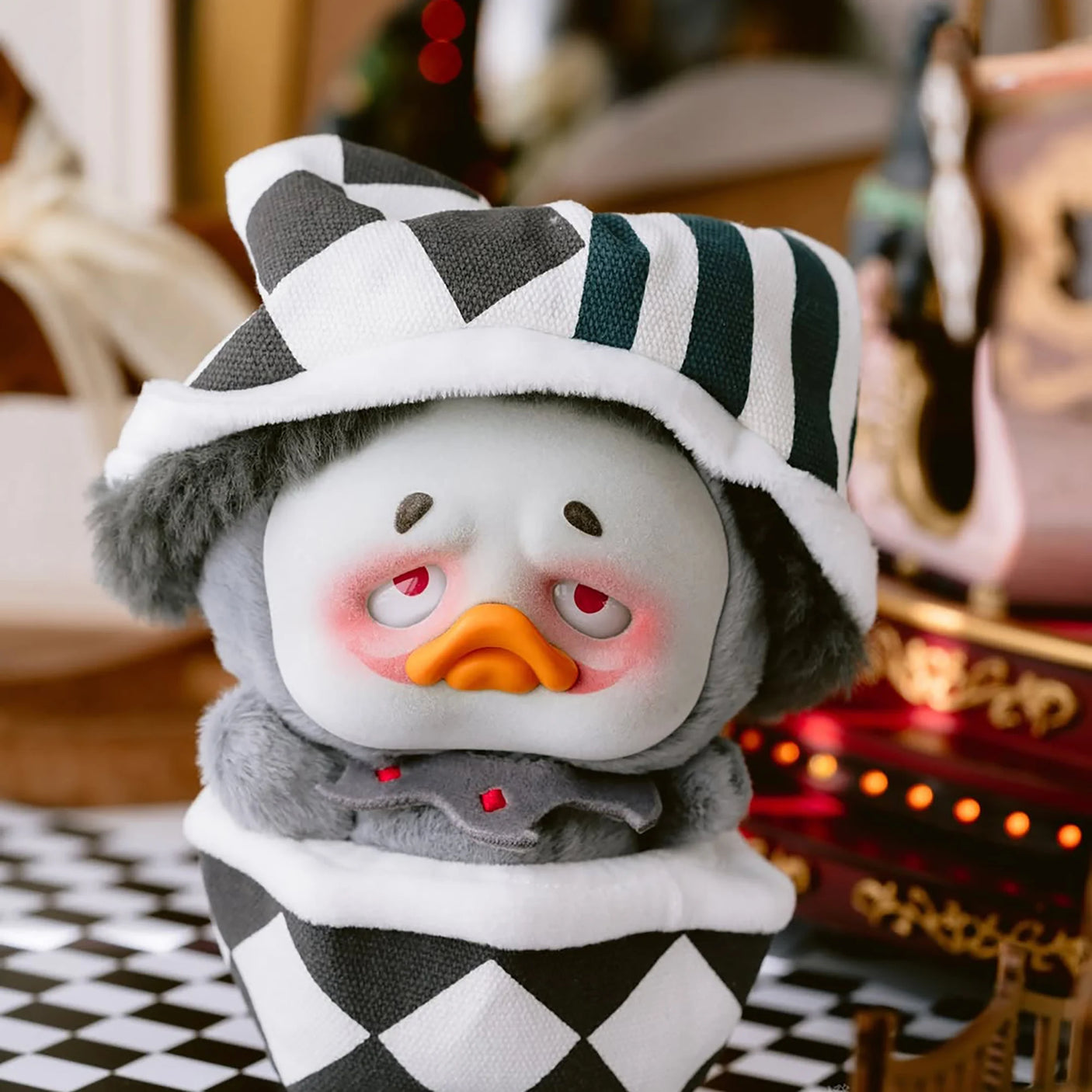 Gray and white plush duck wearing a black-and-white striped hood and horn-style headpiece