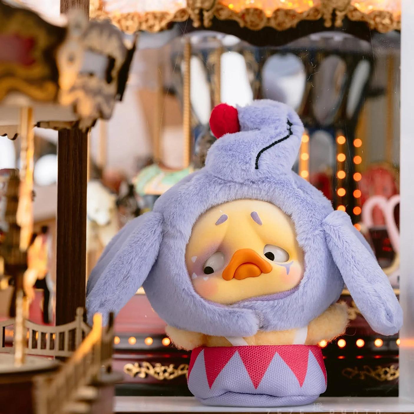 Lavender plush duck with fluffy hood, red pompom, and red-striped outfit