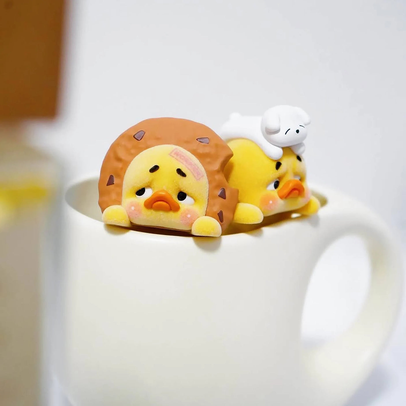 Duck blind box figure lying down with orange headwear and small white companion