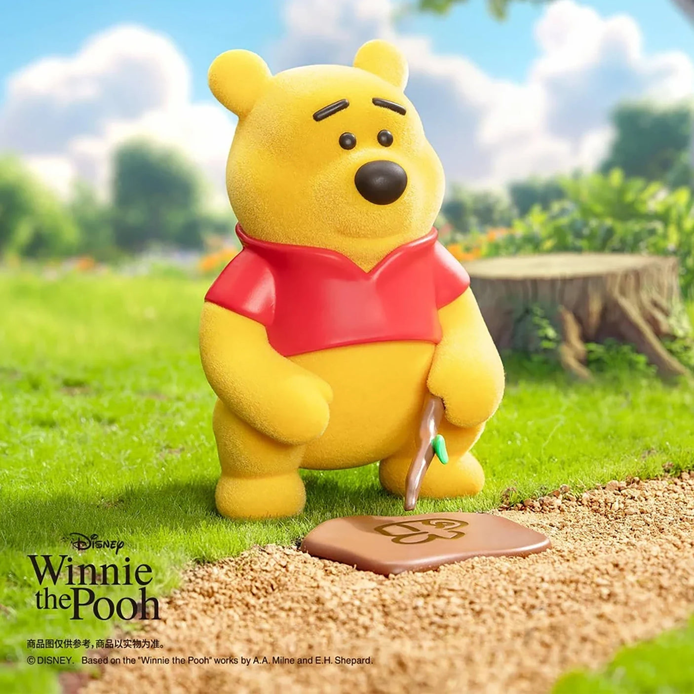 Yellow bear figure in a red shirt standing on grass, holding a small card
