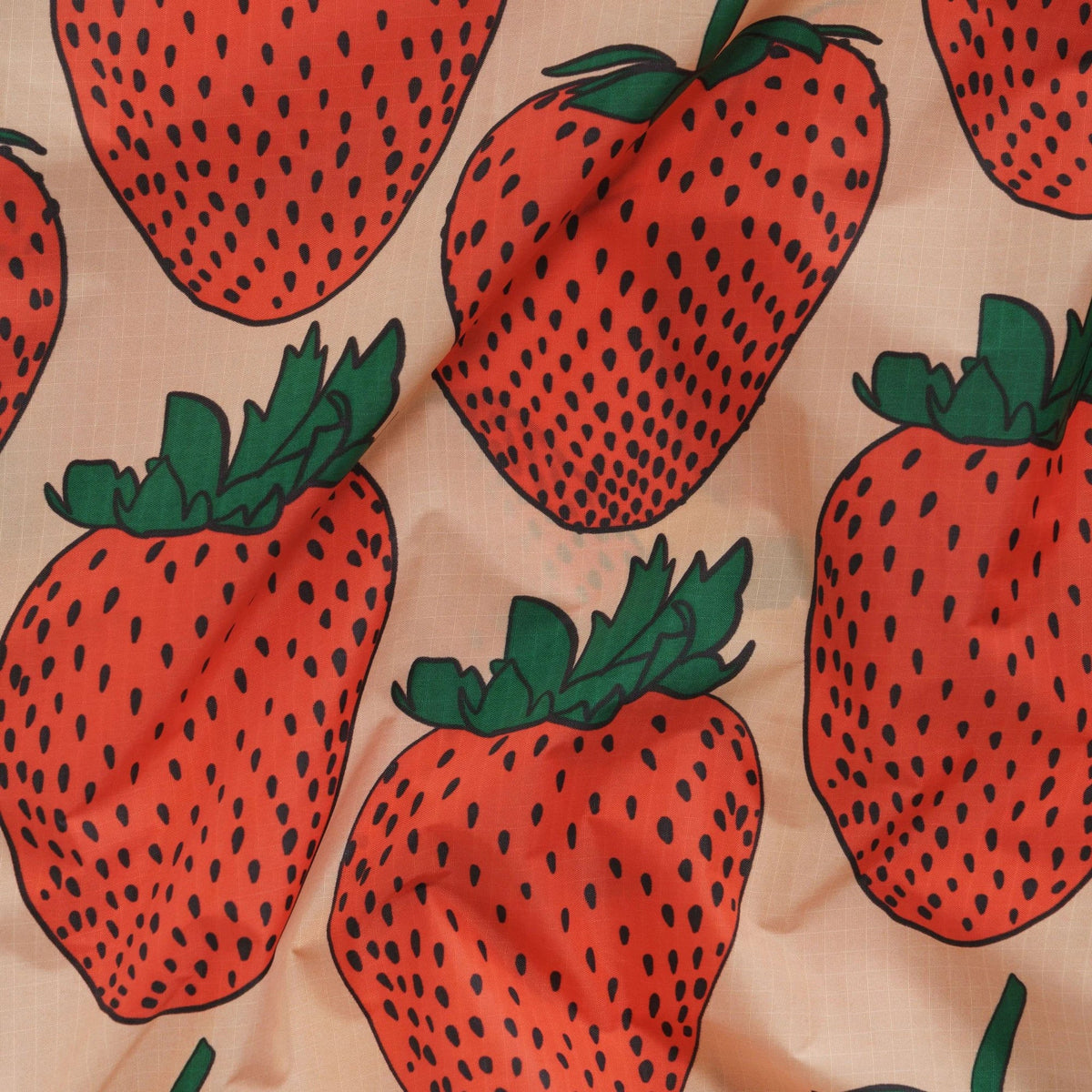 Tote bag fabric close-up with red strawberries and green leaves on cream