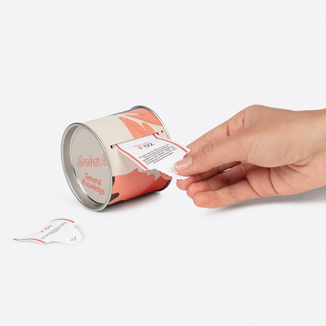Hand pulling a fact card from cylindrical tin of Another Me 100 Daily Curious General Facts, gallery position 1