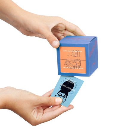 Hands holding blue cube box and blue card from Another Me 30 Day F--k It Challenge, gallery position 1