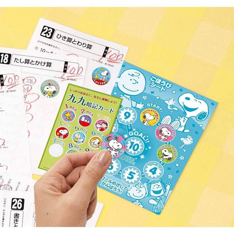 Close-up of hand holding a Snoopy Motivation Sticker from a colorful Japanese study reward card set
