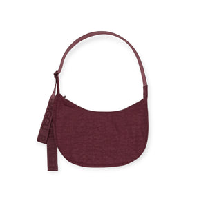 The Baggu Medium Crescent Bag - Mahogany is a maroon, crescent-shaped bag crafted from recycled nylon with an adjustable strap and a "BAGGU" tag.