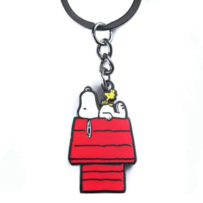 Metal enamel keychain of Snoopy lying on his classic red doghouse with Woodstock perched on top, white background.