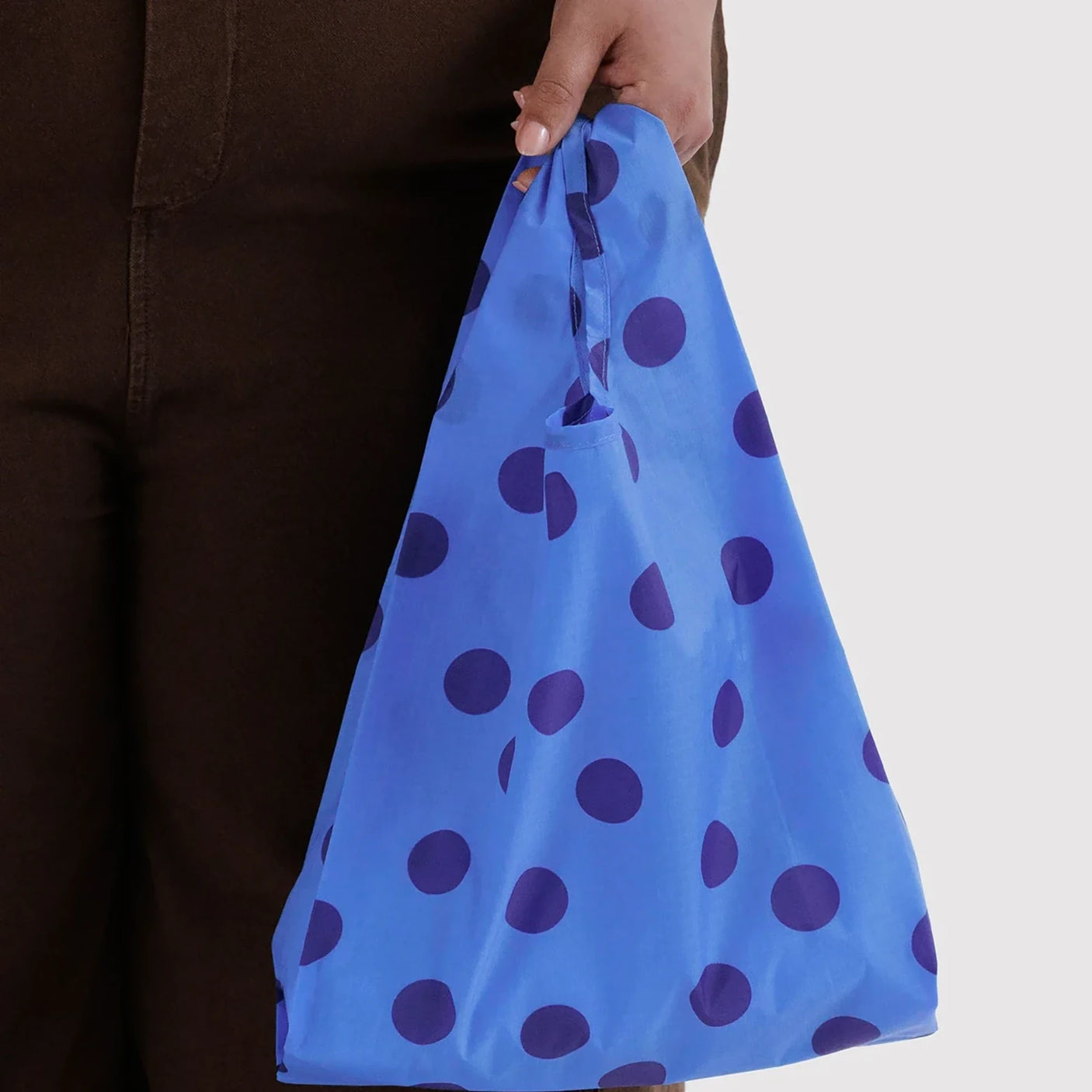 Blue polka dot baby tote bag held by hand, with elastic top opening
