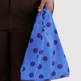 Blue polka dot baby tote bag held by hand, with elastic top opening