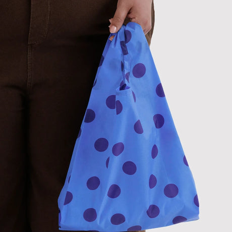 Blue polka dot baby tote bag held by hand, with elastic top opening