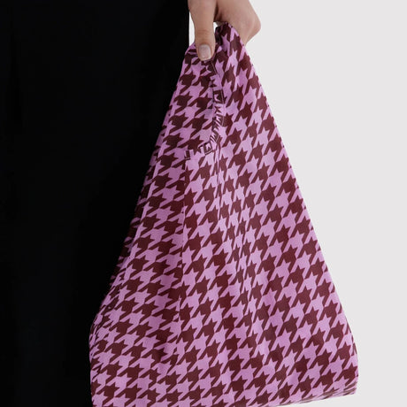 Pink houndstooth Baggu baby tote held by hand, flexible fabric