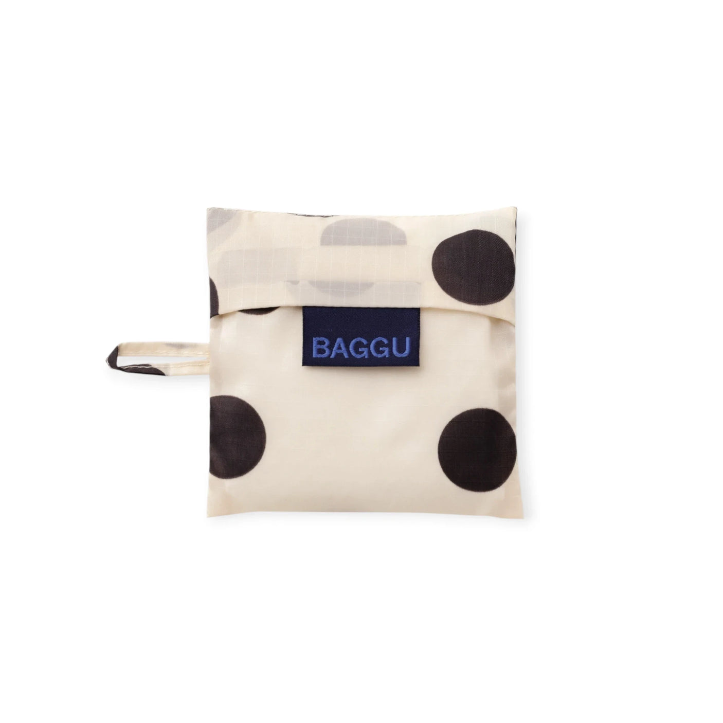 Cream baby tote bag with black polka dots, folded with wrist strap and BAGGU label