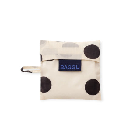 Cream baby tote bag with black polka dots, folded with wrist strap and BAGGU label