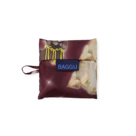 A folded Baby Baggu Bag - Fancy Dogs by Baggu, featuring a maroon and cream dog pattern, made from recycled nylon, packed into a square pouch with a blue BAGGU label and side loop.