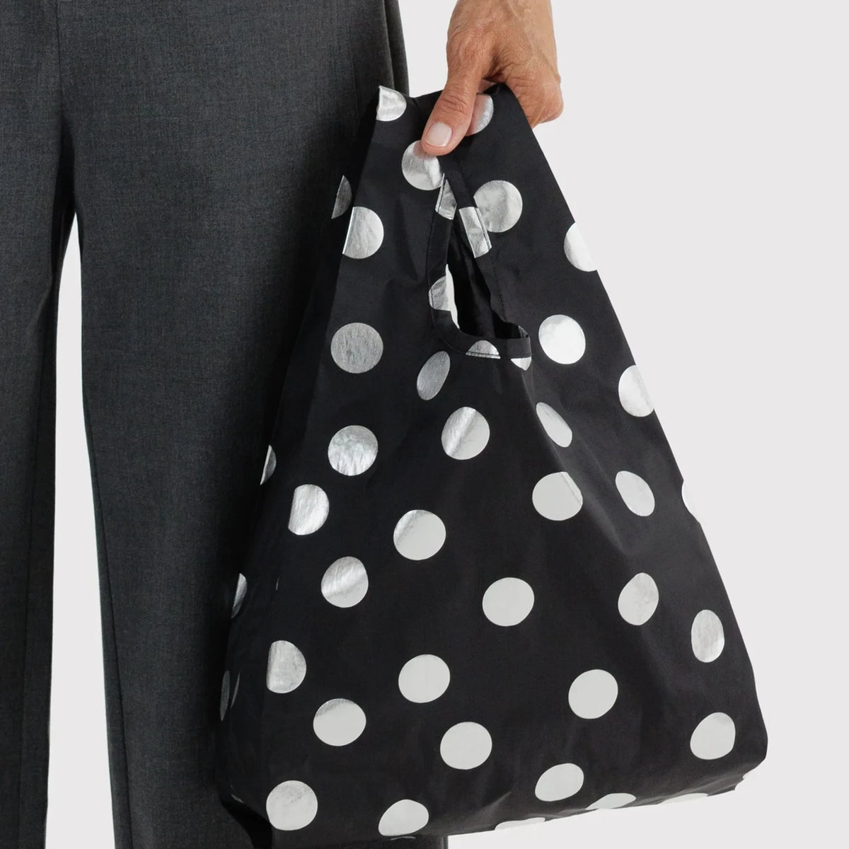 Baggu baby tote bag held in hand, black with silver metallic polka dots