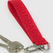 The vivid red Baggu Logo Keychain, made from recycled nylon webbing, features a metal clip for securely attaching to silver keys.