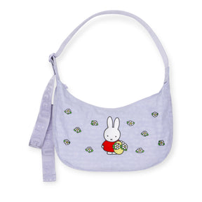 The Miffy x Baggu Medium Nylon Crescent is a lavender crossbody bag with a cartoon bunny and floral details, an adjustable "BAGGU" strap, and recycled nylon—making this playful Baggu accessory perfect for everyday use.