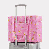 Pink star-print carry-on bag with top handles and luggage sleeve over handle