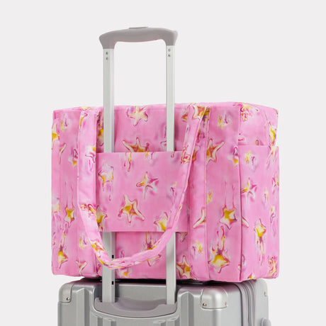 Pink star-print carry-on bag with top handles and luggage sleeve over handle