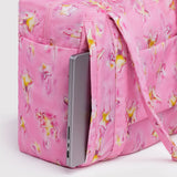 Pink star-print carry-on bag with front zip pocket holding smartphone