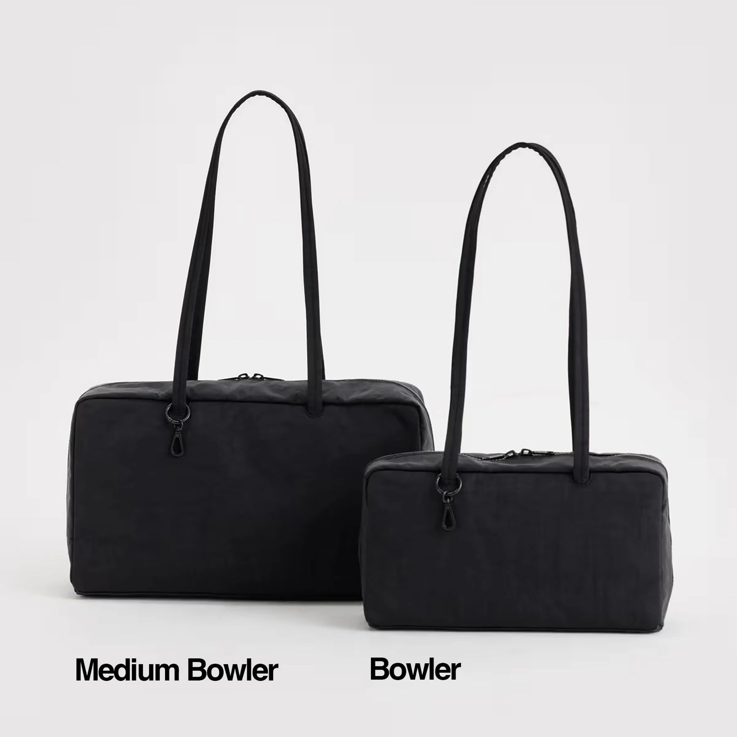 Two black bowler bags with long straps sit side by side on a white background. The left is the Baggu Medium Nylon Bowler Bag - Black by Baggu; the right is labeled "Bowler.