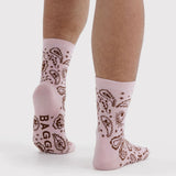 Pink crew socks with brown paisley and star pattern, worn with bare legs