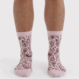 Pink crew socks with brown paisley and star pattern, pair shown on feet