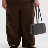 Baggu washed black denim bowler bag held at side, top handles, zip closure.