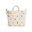 Baggu offers the Duck Bag Medium in Ditsy Floral, a beige tote bag adorned with small, colorful floral embroidery, complete with sturdy handles and an adjustable shoulder strap.