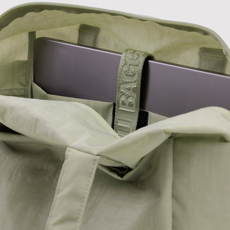 Open light green tote bag showing laptop secured inside with branded strap detail