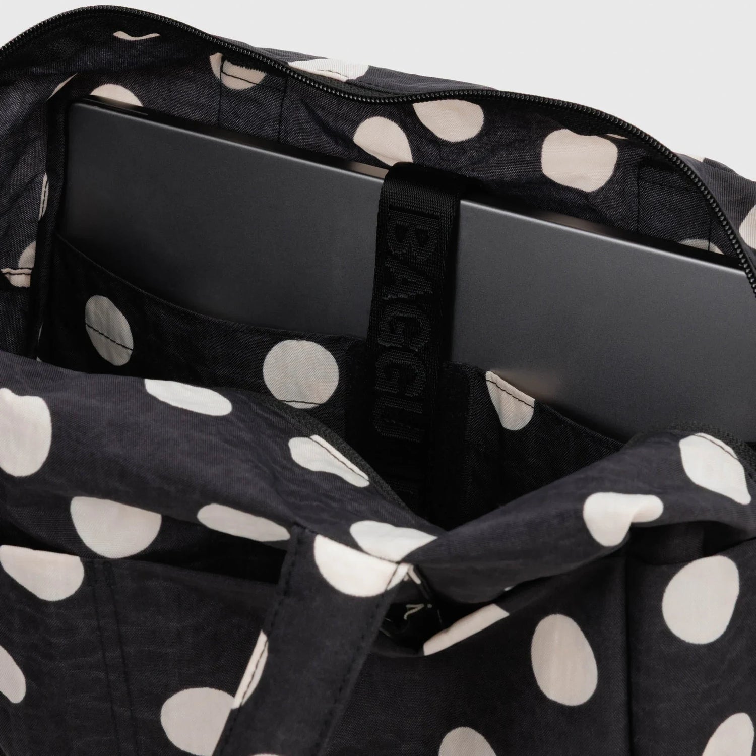 Interior of black polka-dot tote with zip top, padded lining and inner pockets