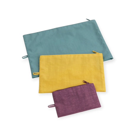 Three canvas zipper pouches in teal, yellow, and plum, stacked in a set.