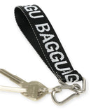 A set of keys hangs on a metal ring attached to the Baggu Keychain - Logo Strap, featuring a black and white design crafted from eco-friendly recycled nylon webbing.