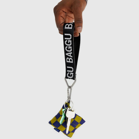 A hand holds a Baggu Logo Keychain - Peony, with keys attached, and adorned with a blue and yellow checkered pattern, made from recycled nylon webbing.