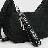 This minimalist accessory, a black shoulder bag crafted from recycled nylon, features a Baggu Logo Strap keychain with two metal keys attached to the strap and a zipper closure.