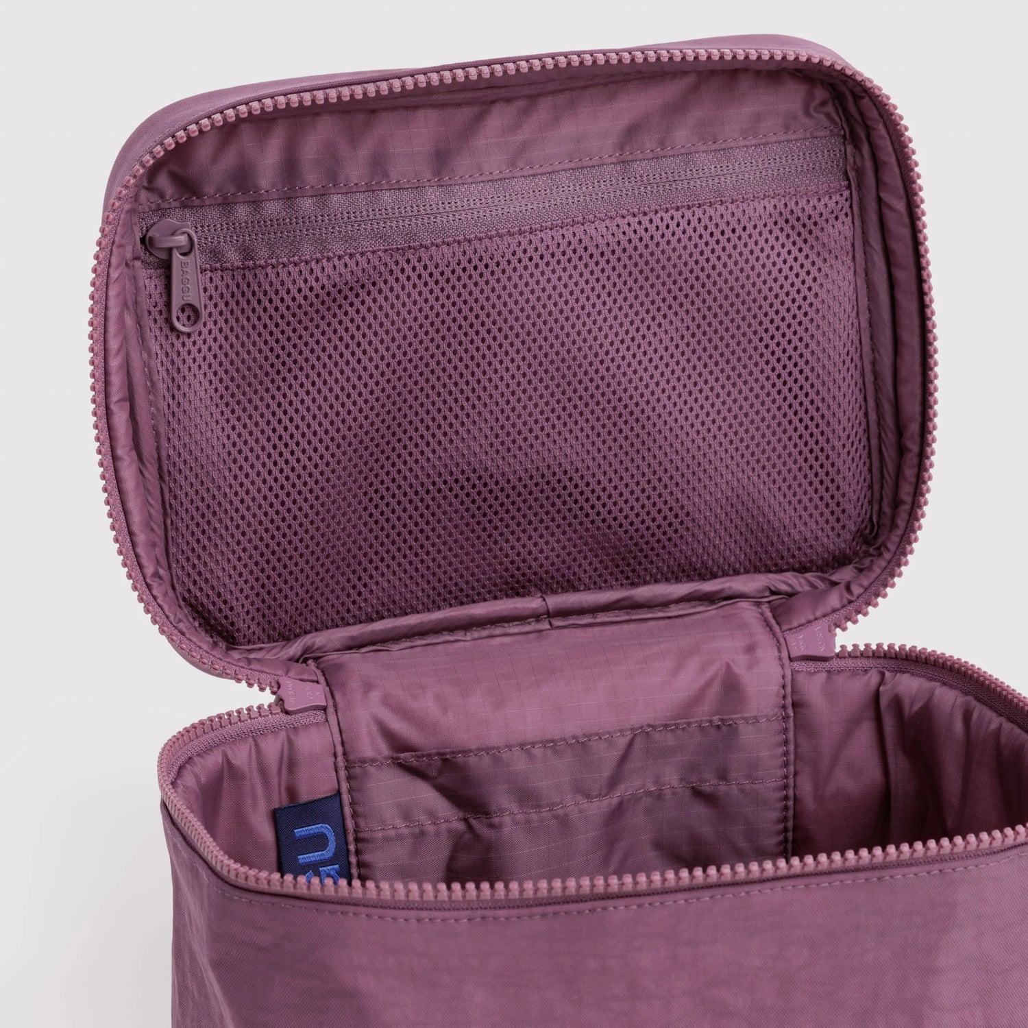 Wild plum cosmetic case interior view with mesh pocket and zipper pull, blue tag