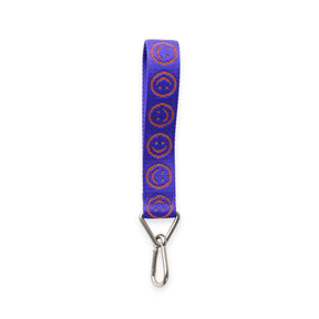 Baggu logo keychain with lapis blue strap and orange smiley circles, metal clip