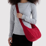 Cherry red crescent shoulder bag worn crossbody with long strap