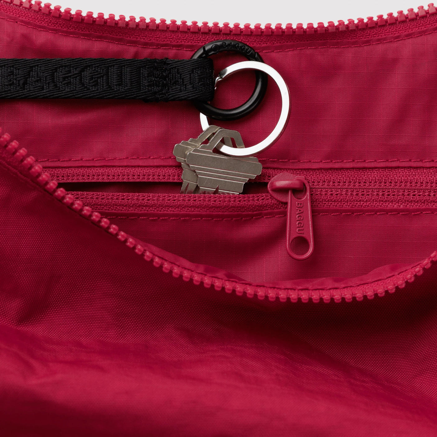 Red nylon crescent bag interior with zipper, key ring, and toggle loop