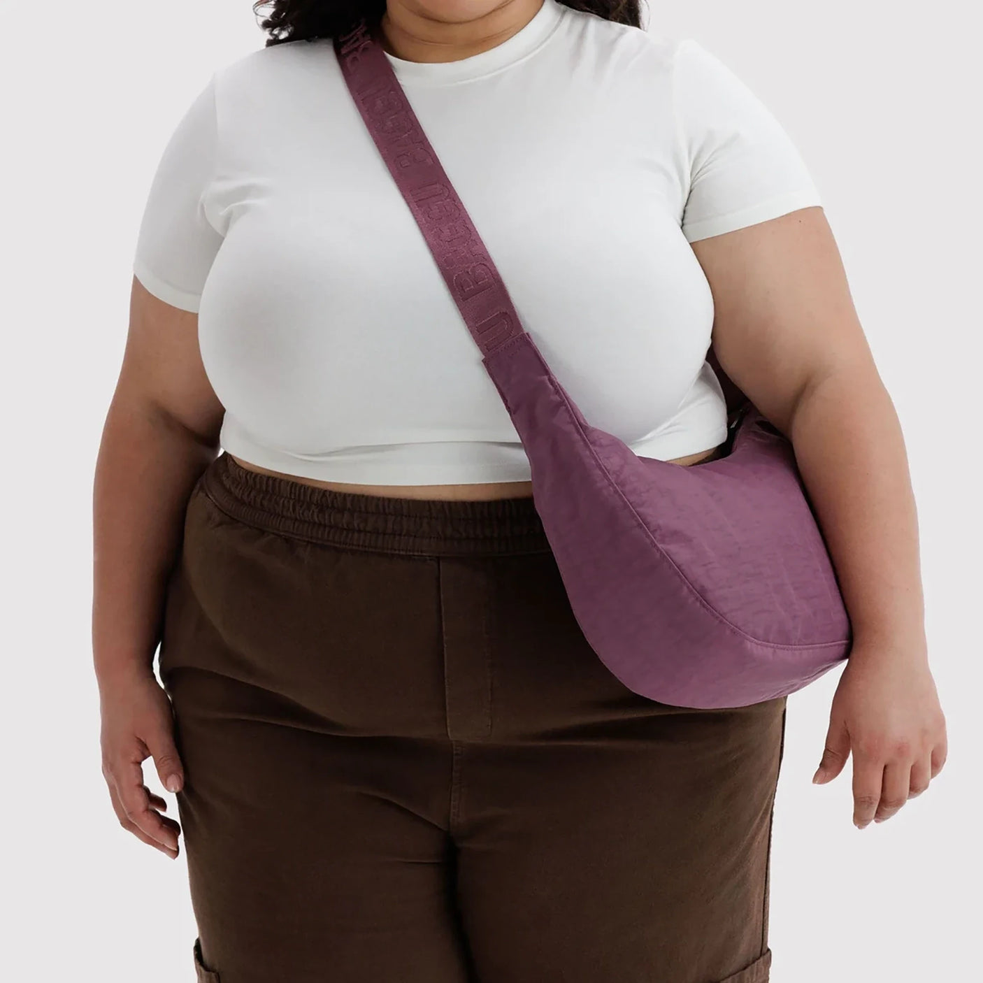 Medium nylon crescent crossbody bag in wild plum, worn on shoulder with adjustable strap
