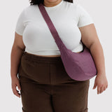 Medium nylon crescent crossbody bag in wild plum, worn on shoulder with adjustable strap