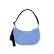 The Baggu Medium Nylon Crescent Bag - Cornflower is designed in a light cornflower blue hue, complemented by a black strap and side tassel, crafted from recycled nylon and displayed on a white background.