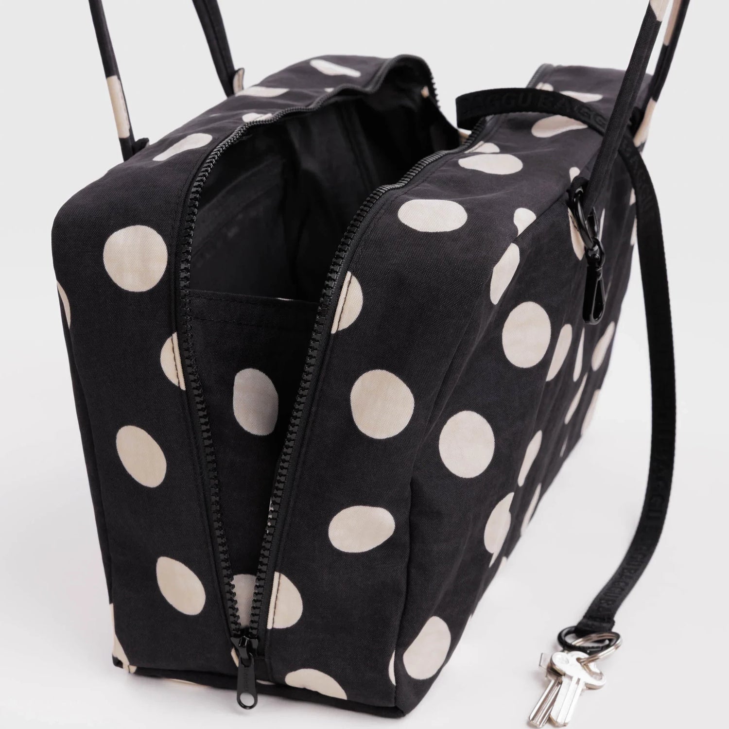 Medium nylon bowler bag in black with cream polka dots, side zippers and metal clasp