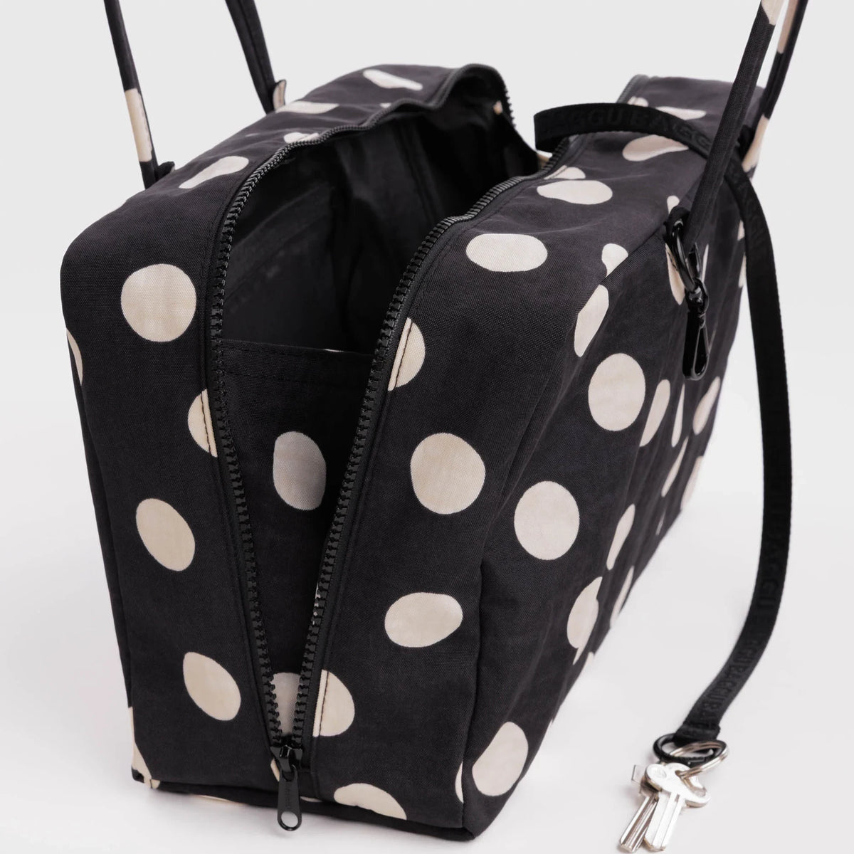 Medium nylon bowler bag in black with cream polka dots, side zippers and metal clasp