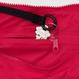 A set of silver keys on a keyring peeks out from the small zippered pocket of the eco-friendly Baggu Medium Nylon Crescent Bag in Candy Apple.